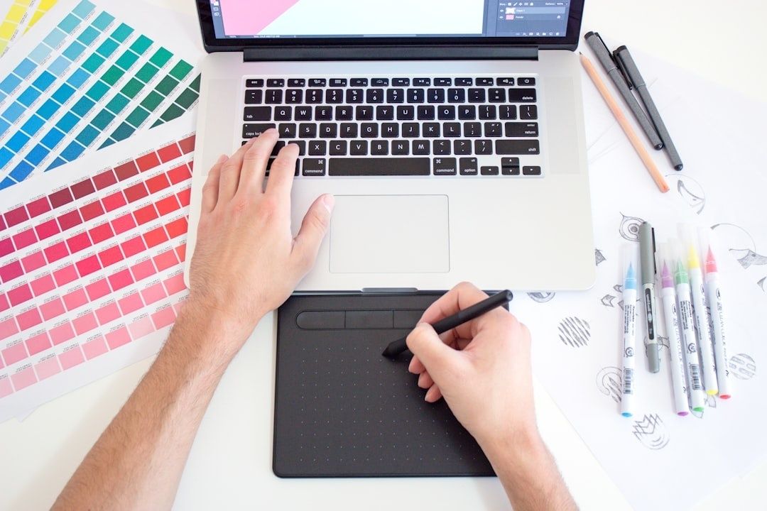 Designer travaillant sur ordinateur avec nuanciers et tablette graphique